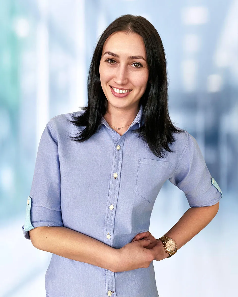 A professional remote headshot of a woman in a light blue shirt from a distributed team rollout.