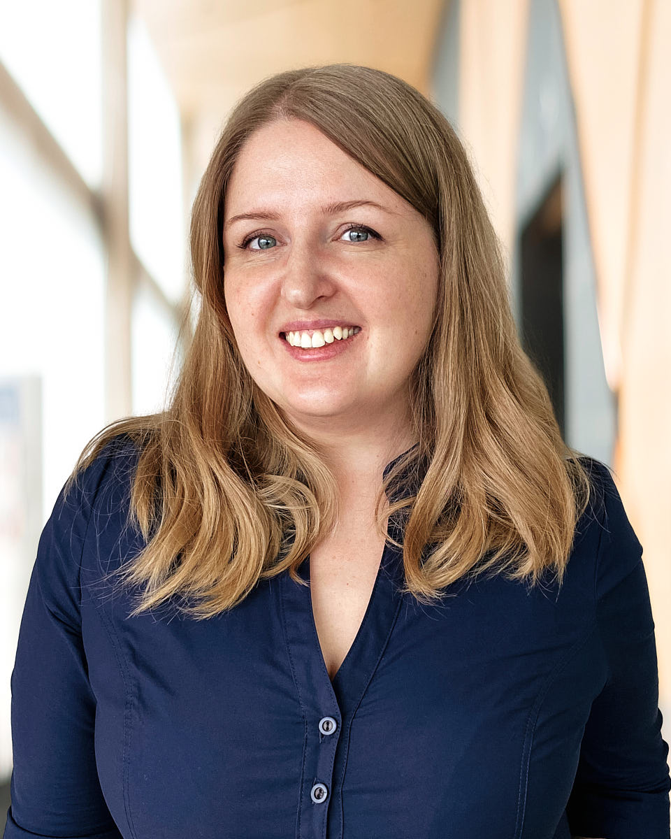 Approachable enterprise headshot of a woman in a blue shirt with a natural expression.