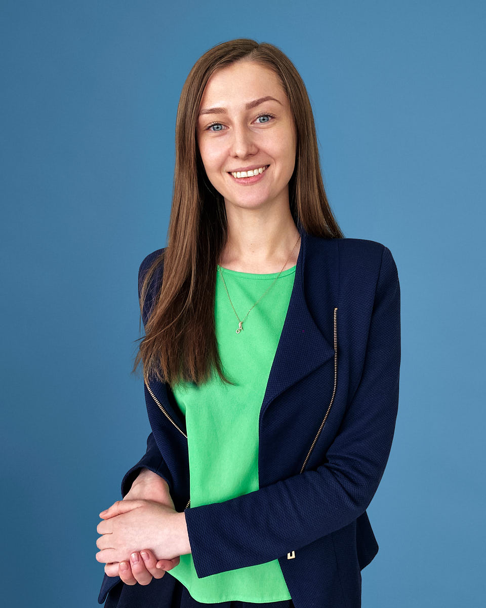 Professional executive headshot of a woman in a green top and blue blazer.