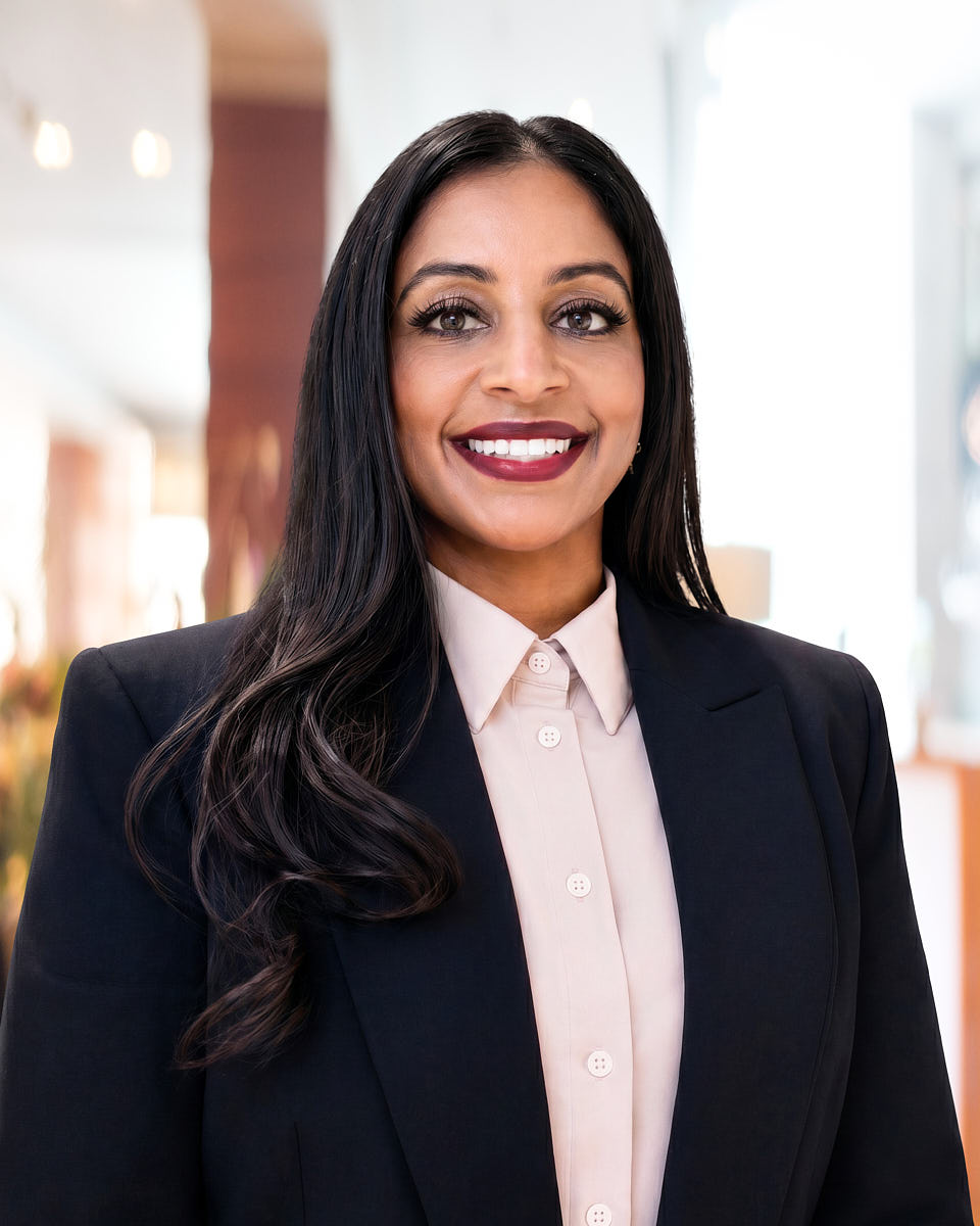 Global employee portrait of a woman in a black blazer with a bright office-style background.