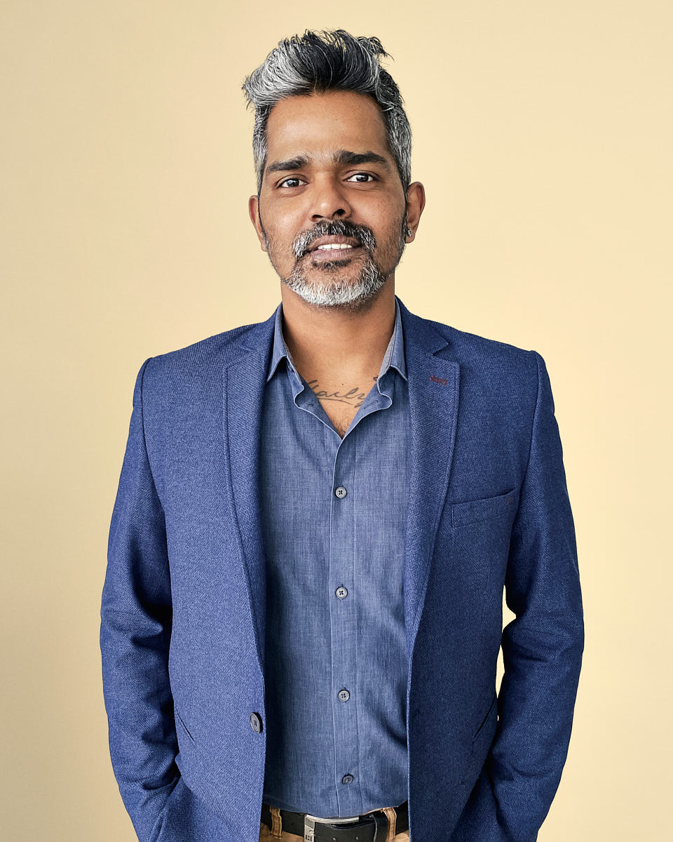Professional startup headshot of a man in a blue blazer with a warm neutral background.