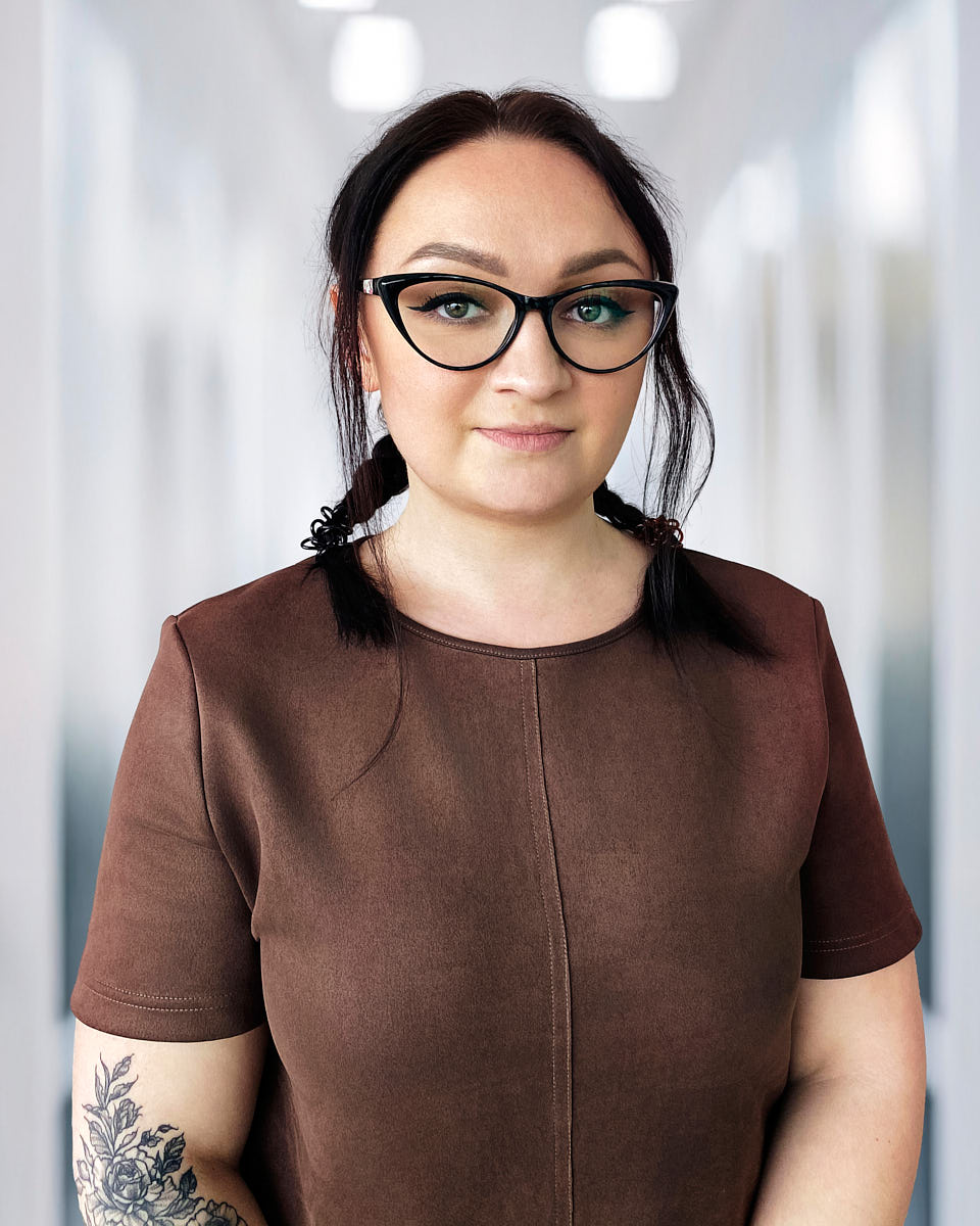 Professional startup team headshot of a woman with glasses in soft office-style lighting.