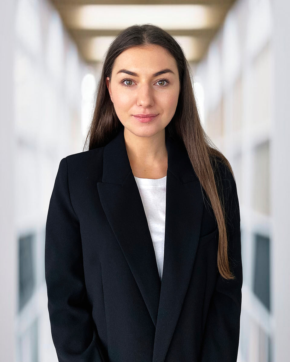 Virtual headshot of a woman in a navy blazer with a clean corporate background.